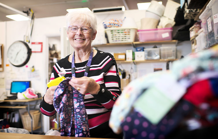 A female volunteer smiles while sorting clothing donations.