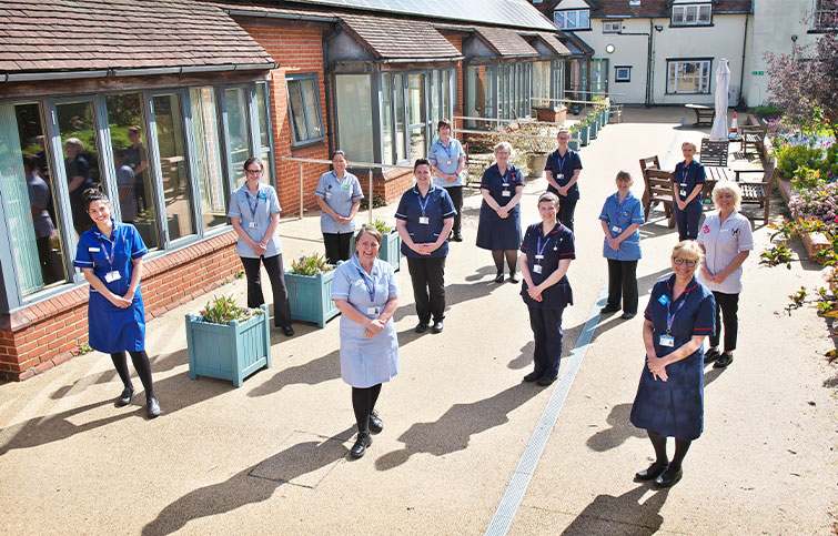 A large group of St Helena nurses smiling in the hospice garden. 