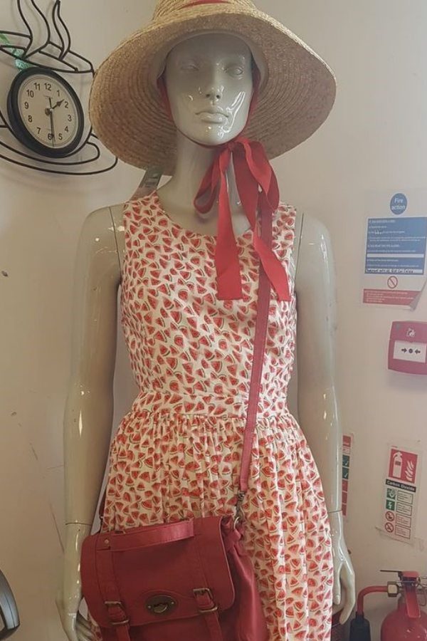 Mannequin dressed in a red and white spotty summer dress, with red bag and a sun hat