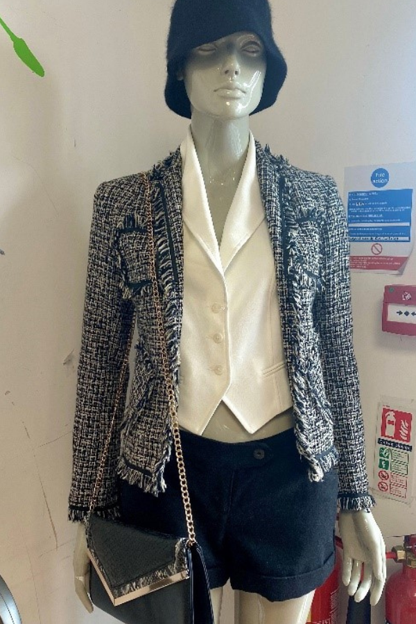Mannequin dressed in black and white blazer, black shorts, white wasitcoat and black accessories