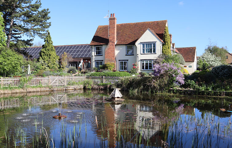 A large pond with reeds and a water feature in front of the hospice building