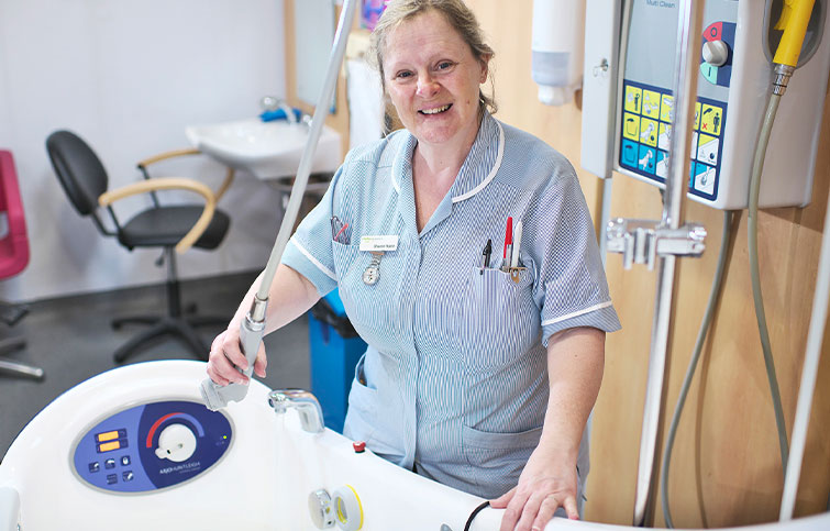 A female clinical support worker standing next to a bath,
