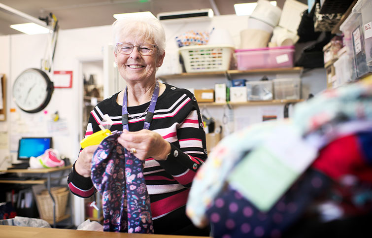 A female volunteer smiles while sorting clothing donations.